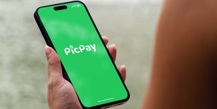 Mulher segurando celular aberto no aplicado do PicPay, que pediu IPO nos EUA com holding de apostas online