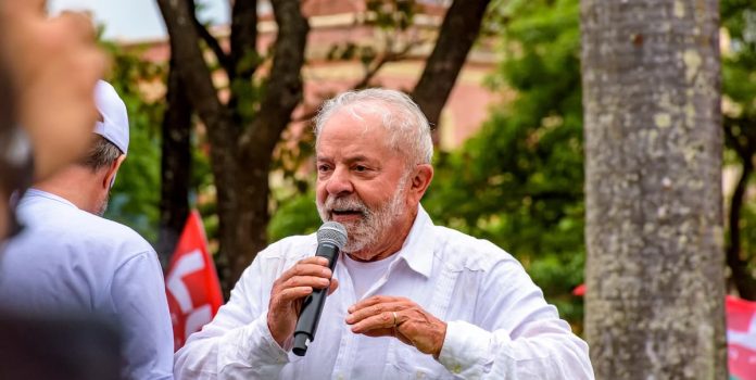 Presidente-Lula-Brasil Presidente Lula, um homem branco de idade avançada e cabelos brancos, discursa com um microfone em mãos.