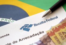 Receita Federal arrecada R$ 3,3 bilhões com apostas no 1º trimestre de 2026 Uma folha da Receita Federal com notas de 20, 10 e 5 reais apoiada na bandeira do Brasil.