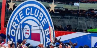 Dezenas de torcedores do Esporte Clube Bahia celebram a chegada do ônibus do clube.