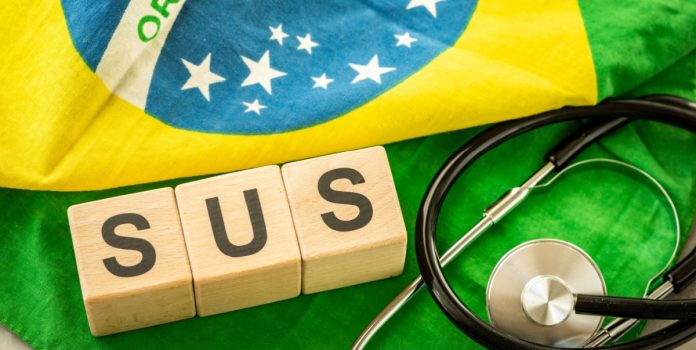 Estetoscópio e blocos de madeira escrito SUS sobre a bandeira do Brasil
