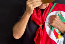 Governo do Rio Grande do Sul realiza audiência pública sobre concessão dos serviços lotéricos Gaúcho olhando para baixo segurando a bandeira do Rio Grande do Sul