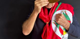 Gaúcho olhando para baixo segurando a bandeira do Rio Grande do Sul