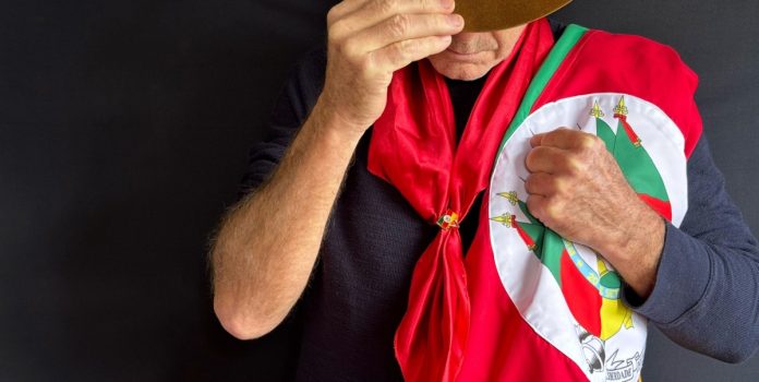 Gaúcho olhando para baixo segurando a bandeira do Rio Grande do Sul