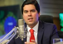Foto tirada de André Fufuca, um homem branco de meia idade em frente a um microfone, líder do Ministério do Esporte.