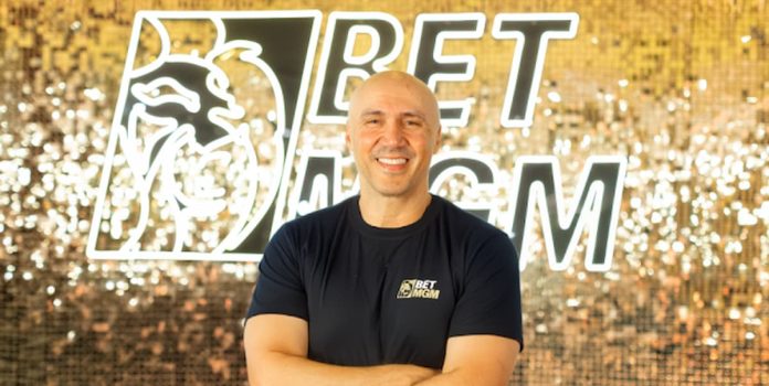 BetMGM-Brasil-CEO-Almir-Ribeiro Foto de Almir Ribeiro, um homem branco careca, em frente à uma parede escrito BetMGM Brazil.