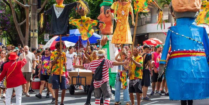 Foto tirada de Carnaval de rua em Belo Horizonte, com dezenas de foliões reunidos.