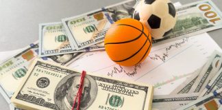 Bolas de basquete e futebol sob maços de dinheiro.