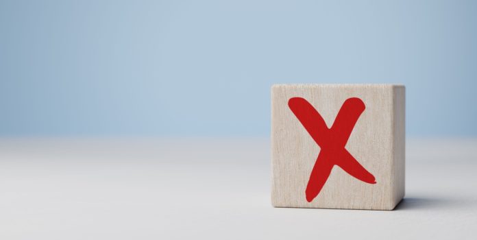 FEBRALOT apoia operação da BetCaixa Cubo com a letra X vermelha escrito sobre a mesa com fundo claro