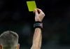 TJD-RJ suspende dois jogadores por um ano em caso de manipulação no Campeonato Carioca 2026 Juiz de futebol mostrando um cartão amarelo.