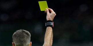 Juiz de futebol mostrando um cartão amarelo.