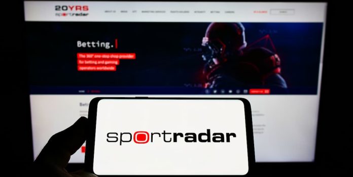 Sportradar Pessoa segurando um celular com um logo da Sportradar.