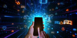 CCT retorna aos trabalhos legislativos de 2026 Mão segurando celular com fundo escuro cheio de símbolos relacionados a redes sociais