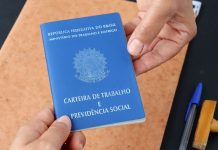 Duas mãos segurando a Carteira de Trabalho do Brasil