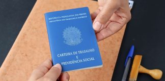 Duas mãos segurando a Carteira de Trabalho do Brasil