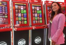 Foto de Celina Guedes ao lado de um dos terminais de videoloteria (VLTs) da EGT.