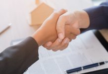 Aperto de mãos em frente à mesa com papéis e caneta
