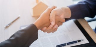 Aperto de mãos em frente à mesa com papéis e caneta