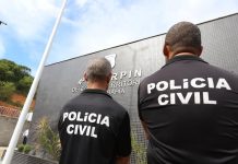 Foto tirada de dois policiais da Polícia Civil, de costas.