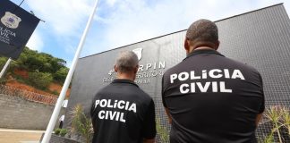 Foto tirada de dois policiais da Polícia Civil, de costas.