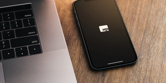 XP Foto tirada de um celular, cuja tela mostra o logo da XP Investimentos.