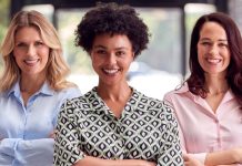Três mulheres sorrindo e com os braços cruzados