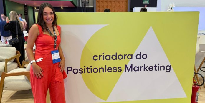 heloisa-bianchi-optimove-entrevista-sbc-summit-rio-2026 Heloísa Bianchi em frente ao estande da Optimove no SBC Summit Rio 2026