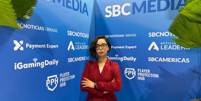 maria-paula-nascimento-kto-analisa-crescimento-da-participacao-feminina-no-esporte-no-sbc-summit-rio-2026-69c6b7872404a Maria Paula Nascimento, da KTO, em frente à divulgação da SBC Media