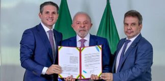 Lei Raul Jungmann determina que bancos e instituições de pagamento bloqueiem contas vinculadas a operadores ilegais Lula segurando o documento oficial da Lei Raul Jungmann ao lado de Hugo Motta e Wellington Lima