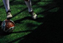Bola de futebol em campo junto a jogador