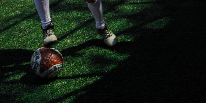 Esportes-Gaming-Brasil-apoia-iniciativa-educacional-contra-manipulacao-de-resultados-do-Ministerio-do-Esporte-e-da-ANJL Bola de futebol em campo junto a jogador