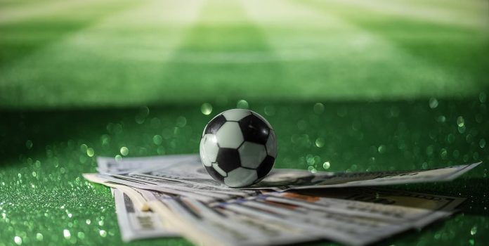 Bola de futebol sobre notas de 100 dólares.