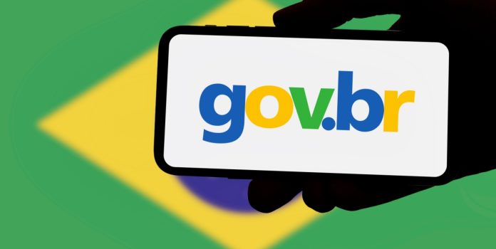 Governo-lanca-campanha-contra-mercado-preditivo Uma mão segurando um smartphone com o logo do governo e a bandeira do brasil no fundo