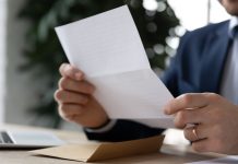 Homem de terno sentado lendo um documento impresso