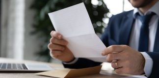 IBJR notifica CNC sobre estudo que associa apostas ao endividamento Homem de terno sentado lendo um documento impresso
