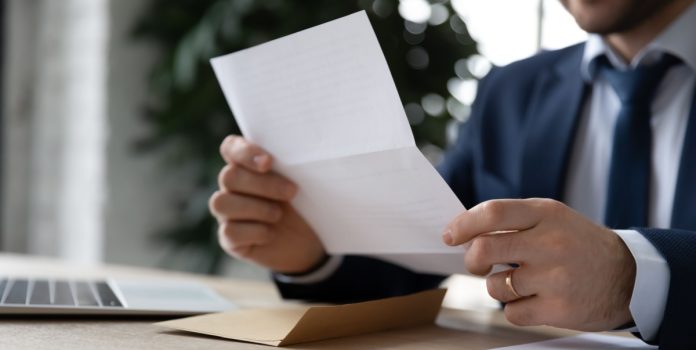 IBJR-notifica-CNC-sobre-estudo-que-associa-apostas-ao-endividamento- Homem de terno sentado lendo um documento impresso