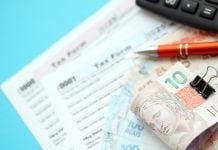 Cédulas de Real, formulário de impostos e calculadora sobre a mesa