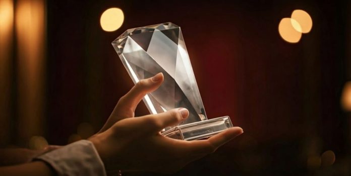 Premio Mãos segurando um troféu prateado.