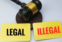 Malhete de juiz com dois cartões amarelos à frente, escritos “Legal” e “Illegal”