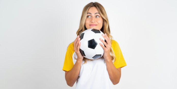 Uma mulher segurando uma bola de futebol em fundo branco
