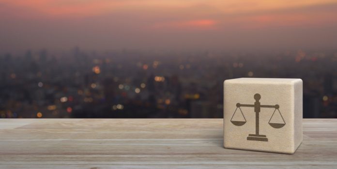 Espaco-Juridico-TozziniFreire_-rosas-preditivos-e-apostas Cubo de madeira com a balança da justiça desenhada