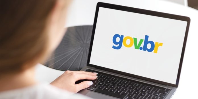 Mulher sentada com notebook no colo acessando o site do governo