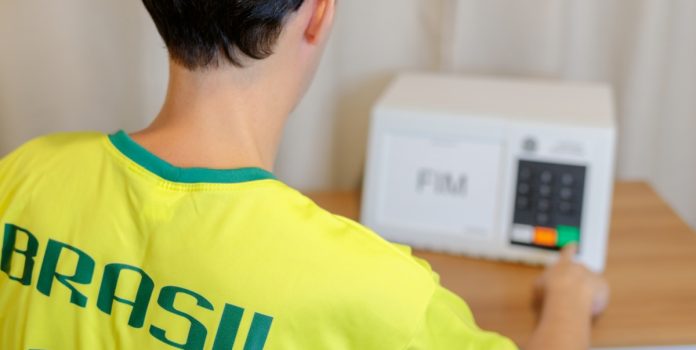Um jovem de costas votando com a camiseta do Brasil