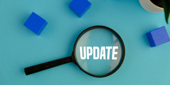 Lupa preta sobre a mesa azul claro com a escrita "Update" em branco e cubos azuis ao redor