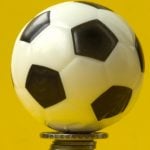 Mercado de apostas projeta movimentar cerca de R$ 31 bilhões durante a Copa do Mundo 2026 Uma bola de futebol em cima de uma pilha de moedas e com fundo amarelo