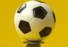Mercado de apostas projeta movimentar cerca de R$ 31 bilhões durante a Copa do Mundo 2026 Uma bola de futebol em cima de uma pilha de moedas e com fundo amarelo