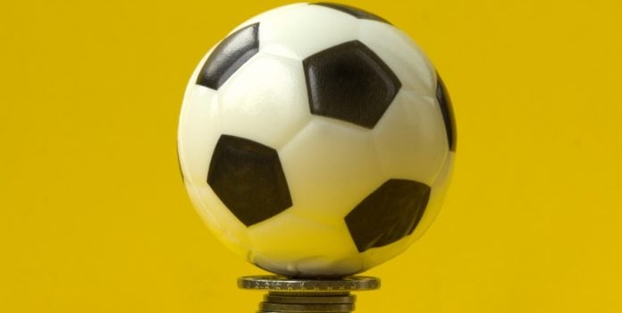 Mercado-de-apostas-projeta-movimentar-cerca-de-R-31-bilhoes-durante-a-Copa-do-Mundo-de-2026 Uma bola de futebol em cima de uma pilha de moedas e com fundo amarelo