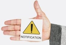 AGU solicita remoção imediata de perfis no YouTube que promovem apostas ilegais Uma mão segurando um papel escrito notificação em inglês com um símbolo amarelo de alerta