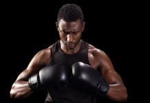 Betano patrocina websérie Raízes do Pódio sobre trajetórias de atletas negros Lutador negro coloca as luvas de treino em um fundo preto