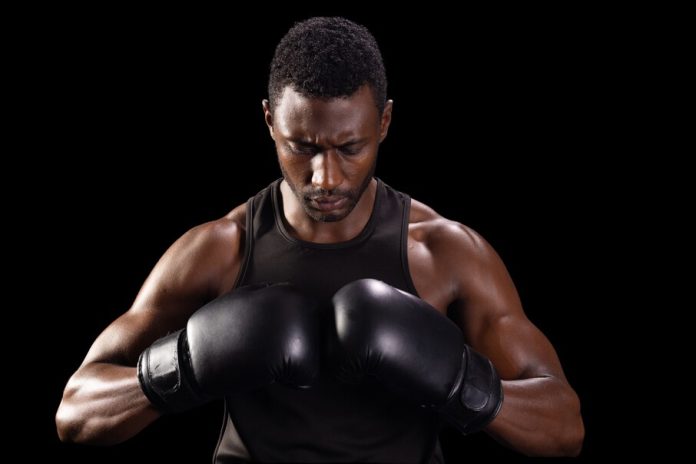 Focused,African,American,Boxer,Prepares,For,A,Match,,With,Copy Lutador negro coloca as luvas de treino em um fundo preto